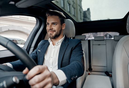 business man smiling at the wheel of a car