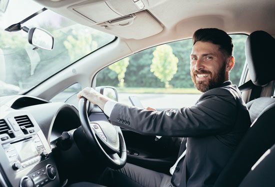 Young bearded man behind the wheel of a hatchback