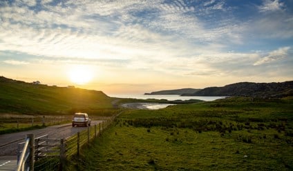 car driving under cloudy sky during sunset