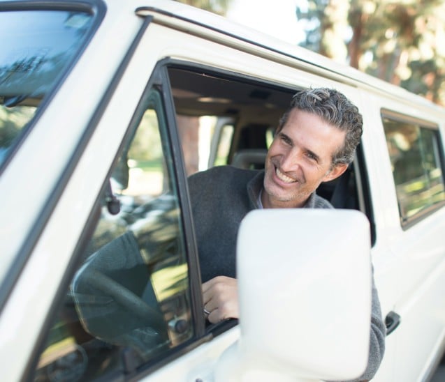 man in grey sweater leaning on van window
