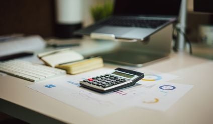 A modern workspace with a laptop, calculator, and documents on a desk, perfect for finance tasks.
