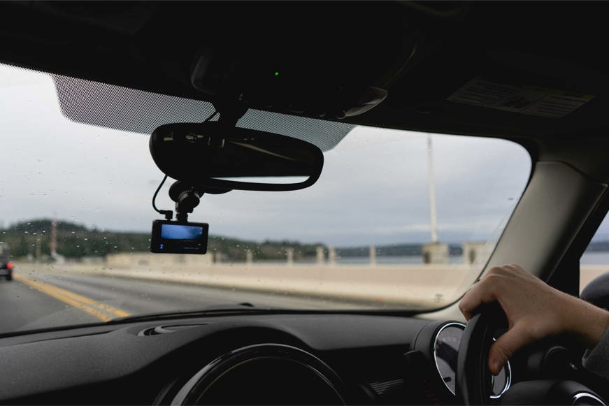 photo of a person driving with a dash cam in the windshield