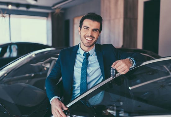 Businessman enjoying new car holding the car keys of his new car