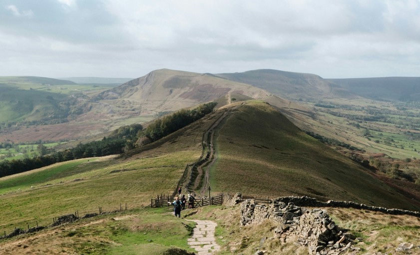 a winding path leads over rolling green hills under clouds