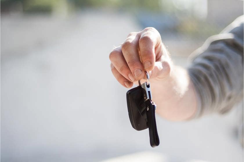 Person in grey jumper holding black car keys