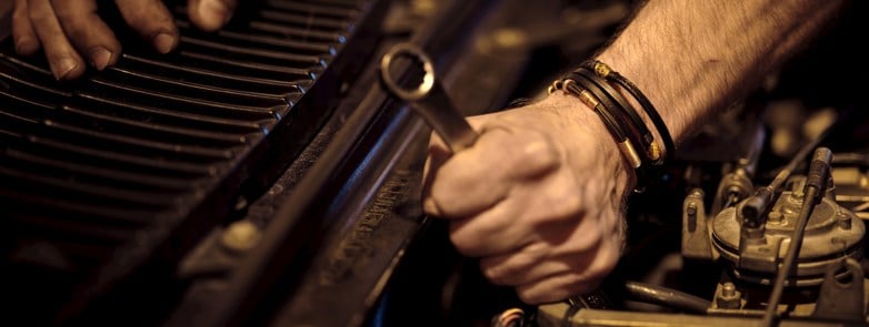 A mechanic inspecting an engine with a wrench in hand