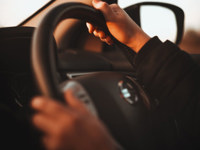 Person driving a Nissan car with both hands on the steering wheel