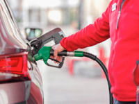 Person in red jacket refuelling a car