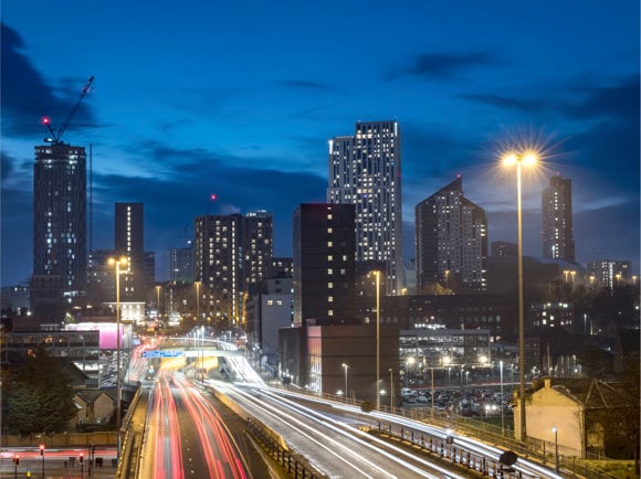 Cityscape night view of the Leeds skyline, showing offices, traffic and high rise apartment buildings.