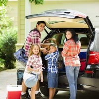 young family loading luggage into suv