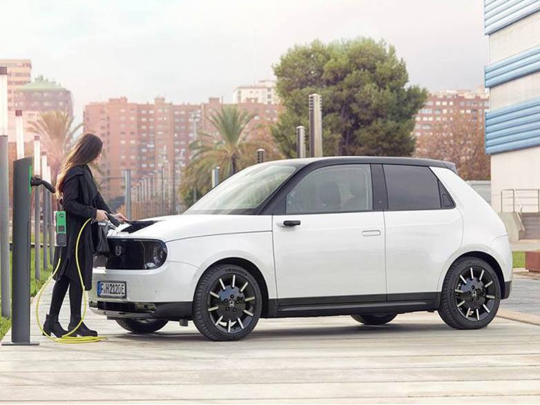 young woman charging honda e hatchback