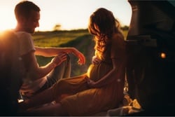 Pregnant woman relaxing by car