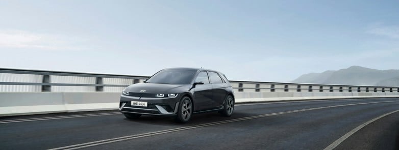 a black car driving down a highway next to a bridge