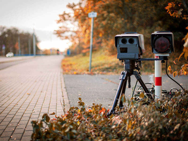 Radar speed camera at the roadside next to shrubbery