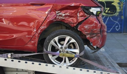 Damaged red car on a recovery truck