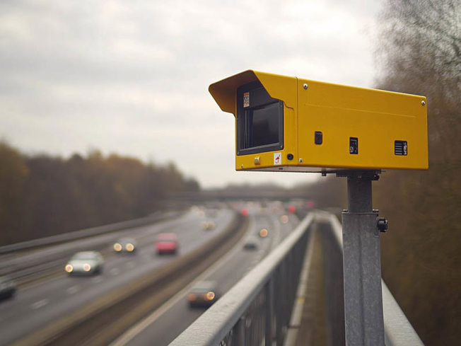 Yellow speed camera looking over a road