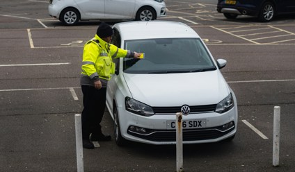 parking attendant putting fine on car