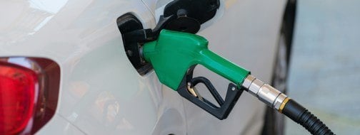Gas pump nozzle in the fuel tank of a white car