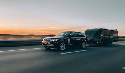 A car towing a trailer on a road.