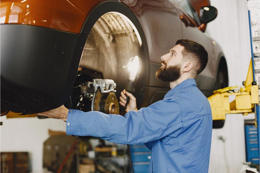 Mechanic in blue overalls inspecting the brakes of a vehicle