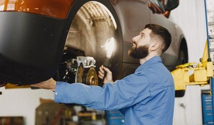 Mechanic in blue overalls inspecting the brakes of a vehicle