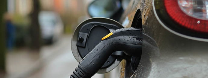 Electric vehicle plugged into charge on the side of the road