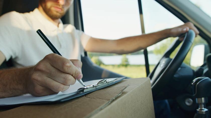 Man sitting in a van writing on a piece of paper