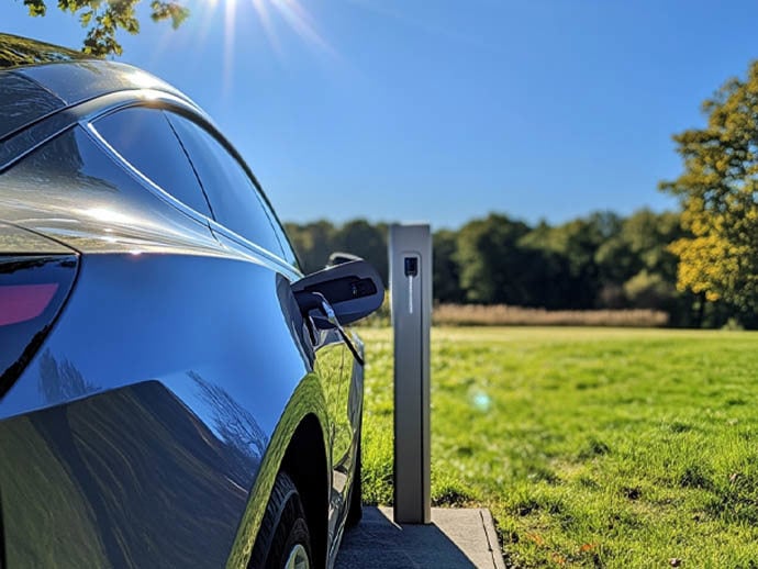 Electric car charging on a sunny day surrounded by lush green grass