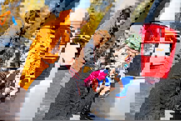 Family putting wellies on their children sat in the back of a car