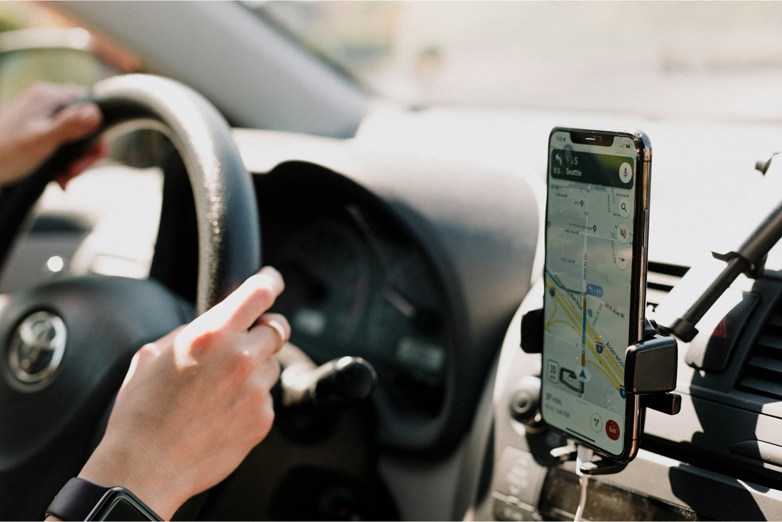 Person driving a car with phone on the dashboard