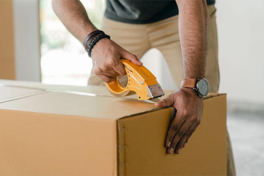 man taping carrying box with scotch tape