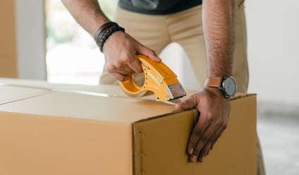 man taping carrying box with scotch tape