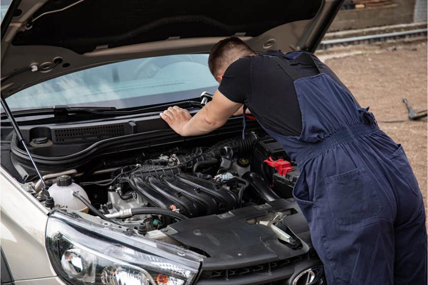 A mechanic in blue overalls fixing the windscreen wpers of a car