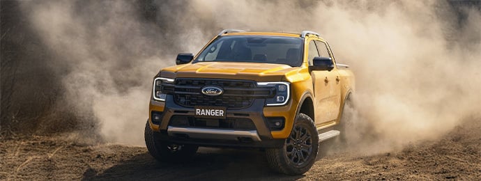 Ford Ranger pickup truck kicking up dust while off-roading on a rugged dirt trail