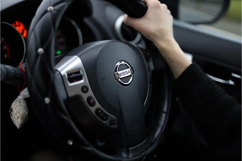 Person holding a nissan steering wheel