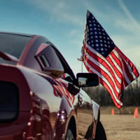 a-red-car-with-an-american-flag-on-top-of-it