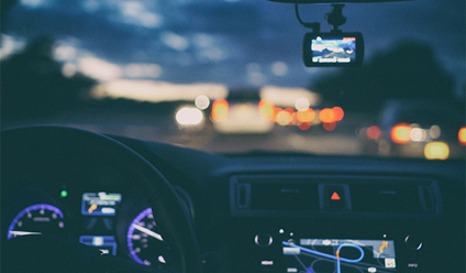 A sunset from the view point of behind a car steering wheel. 