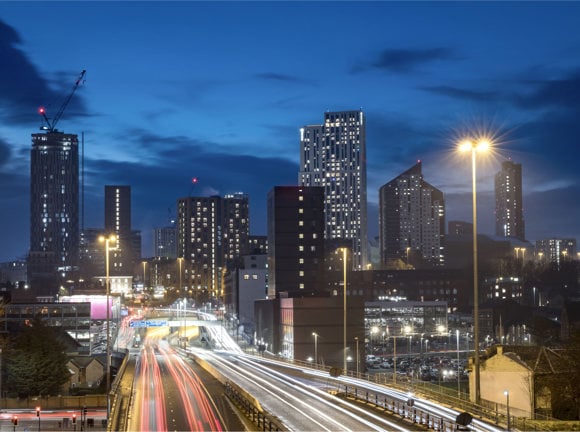 Cityscape night view of the Leeds skyline, showing offices, traffic and high rise apartment buildings.