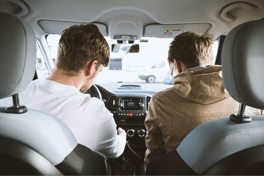 two men sitting in the front of a car