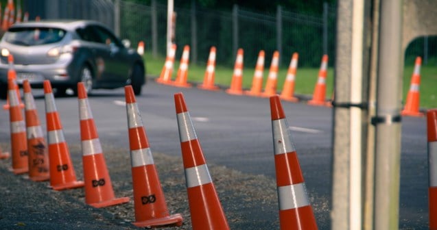 a car driving down a road lined with orange cones