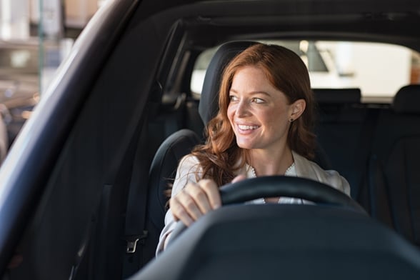 woman sitting in car looking away while trying new automobile