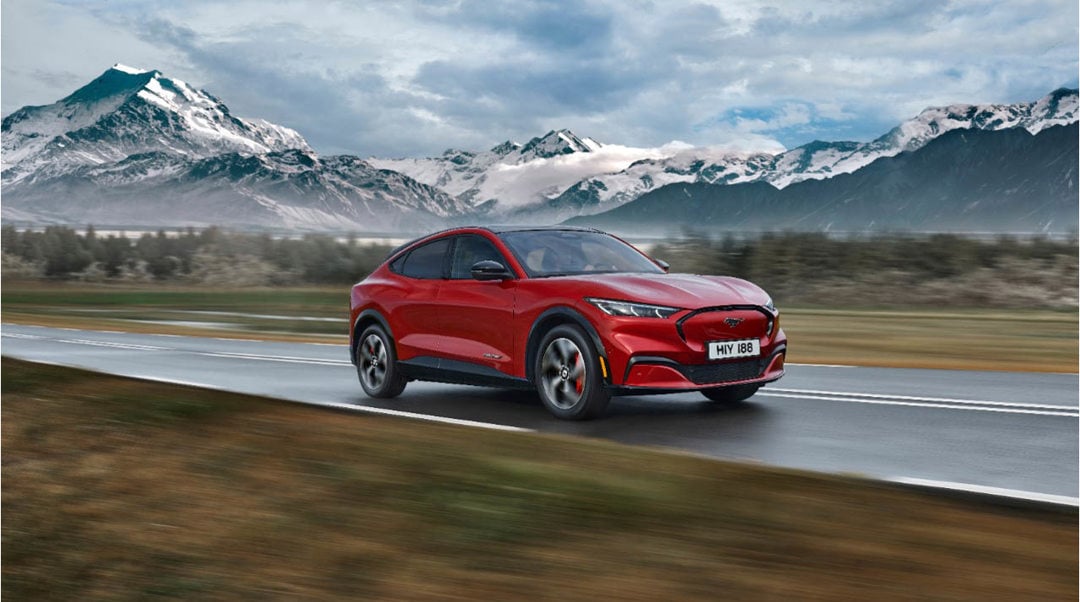 Ford Mustang Mach-E lease car in red driving on the road