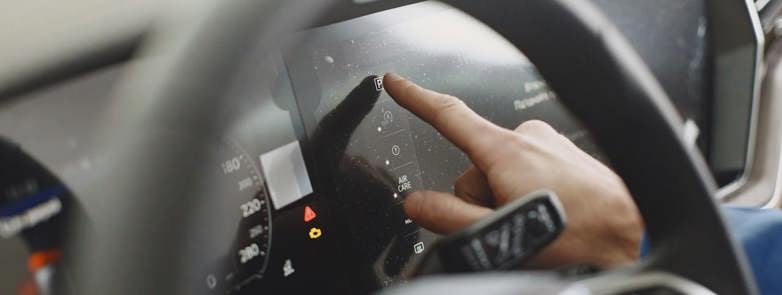 A driver using a cars touchscreen infotainment system