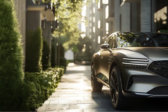 Close-up of a luxury SUV parked on a sunlit urban street with modern buildings and trees in the background