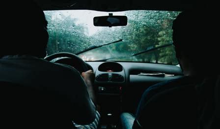 Two Men Inside Moving Vehicle with rain outside