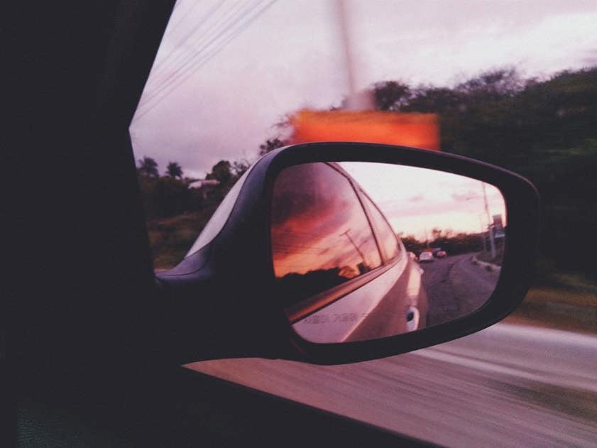 Car wing mirror showing the road behind