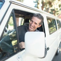 man in grey sweater leaning on van window