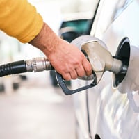 a man pumping gas into his car at a gas station