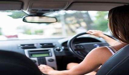 A young woman behind the wheel of a car.