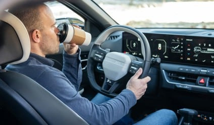 a man driving a car with a cup in this hand